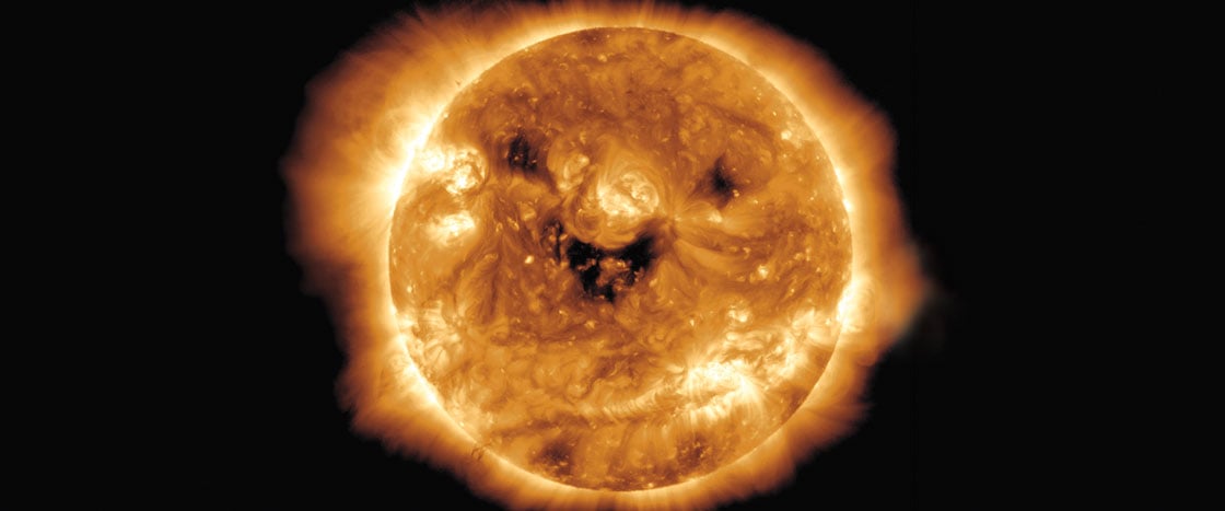 The Sun showing bright orange surface with dark sunspots and glowing corona
